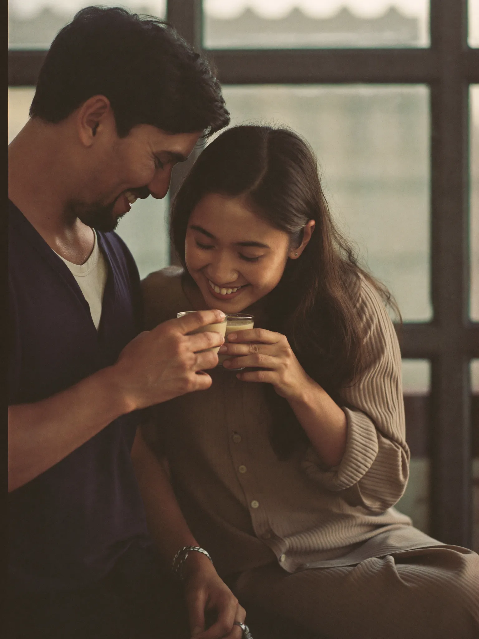 A young Nepali couple sharing chiya in soft window light